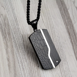 Macro detail of dog tag pendant with crocodile texture and inlaid zircon on ball chain