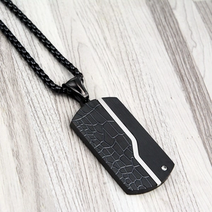 Detail view of matte black military dog tag necklace with embossed crackle texture and zircon