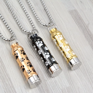 Detailed macro view of paw print urn necklaces in rose gold, black, and gold metal finishes