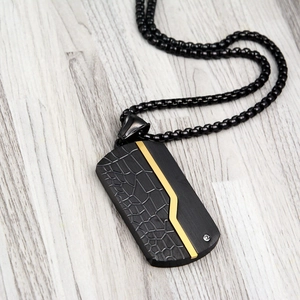 Detail of black matte military dog tag pendant with gold line and crocodile texture