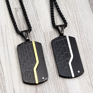 Detail of black titanium dog tag necklace with crocodile texture and inlaid crystal