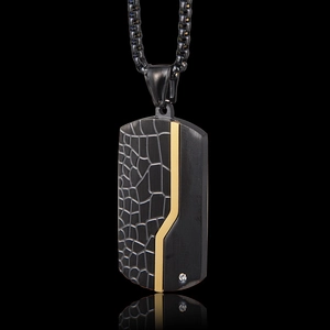 Detail of black matte dog tag pendant with golden trim and luxury crocodile texture