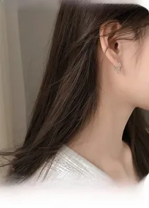 Close-up of a minimalist silver hoop earring with a small solid bead on a female ear