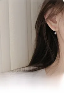 Close-up of minimalist silver bead hoop earrings worn on ear showing delicate style