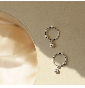 Macro view of silver bead hoop earrings with polished spheres on a matte display