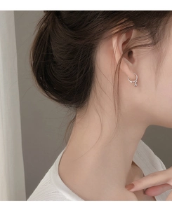 Close-up of minimalist silver ball drop earring worn on small earlobe for a clean look