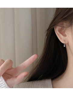Close-up of small silver bead hoop earring worn on earlobe for a minimalist style