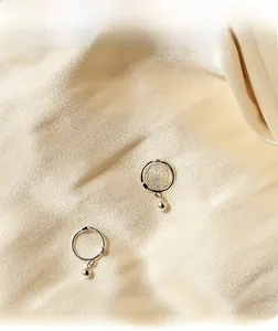 Macro shot of silver minimalist hoop earrings with solid round beads on silk fabric