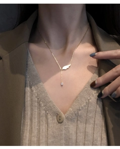 Gros plan d'un collier en Y doré avec ailes d'ange et zircon goutte porté par un mannequin