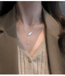 Gros plan du collier à pendentif aile dorée et cristal goutte sur un mannequin femme