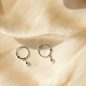 Minimalist silver bead hoop earrings on champagne silk fabric with macro perspective