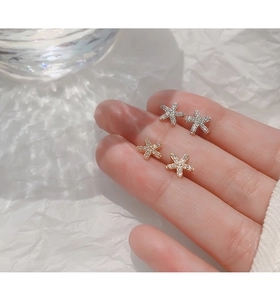 Gros plan de boucles d'oreilles étoiles en or et argent avec zircons blancs