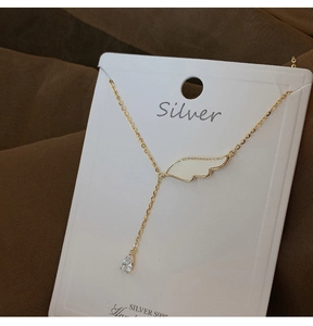 Détail macro du pendentif aile d'ange en argent S925 et zircon sur collier chaîne Y doré