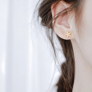 Puce d'oreille étoile en argent S925 doré avec zircons portée délicatement sur l'oreille