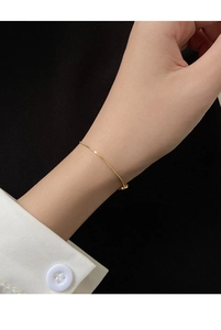 Close-up of minimalist gold snake bone chain bracelet worn on a female wrist