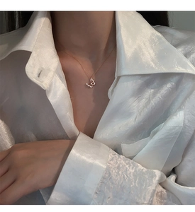 Nahaufnahme der s925 Silber Schmetterlingskette mit glänzenden Diamanten auf Seidenhemd
