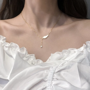 Collier doré élégant avec pendentif aile en nacre et zircon sur le cou du mannequin
