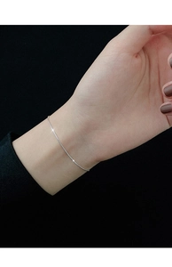 Close-up of minimalist S925 silver snake chain bracelet on wrist with elegant metallic luster