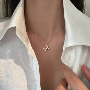 Elegante rotgoldene Schmetterlingskette mit Zirkonia, getragen auf weißer Bluse für Damen