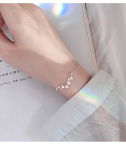 Close-up of S925 sterling silver ginkgo leaf bracelet on wrist with soft lighting
