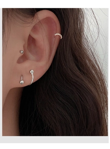 Close-up of minimalist silver spiral earrings and ear cuffs on a female model