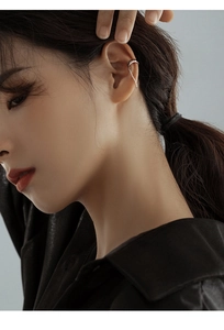 Minimalist silver ear cuff with delicate metal chain shown on a model's ear