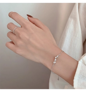 Detail of s925 silver leaf bracelet and wavy ring on hand with elegant aesthetic