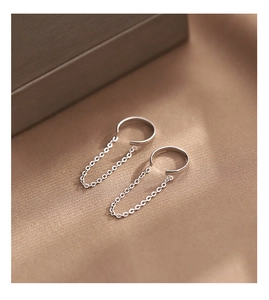 Detailed close-up of 925 sterling silver chain ear cuffs on soft silk fabric background