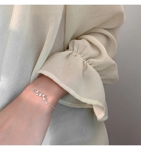 Detail of s925 silver ginkgo leaf bracelet worn with an elegant chiffon sleeve
