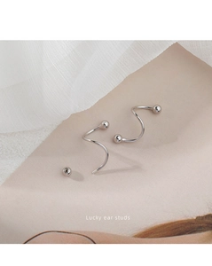 Detail view of silver spiral ear studs with round backing on beige textured paper background
