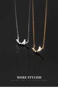 Close-up of silver and gold butterfly necklaces with small diamonds on black background