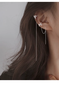 Close-up of silver lightning bolt earrings with zircon studs and long tassel chain
