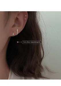 Close-up of minimalist sterling silver spiral earring studs worn by a model