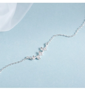 Macro view of silver ginkgo leaf pendants with brushed texture on a delicate chain