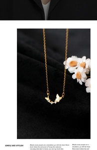 Detailed view of a gold butterfly necklace with white zircon on a black velvet background