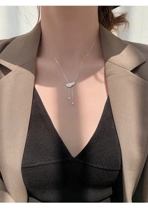 Détail du collier plume argentée avec diamants scintillants et longues chaînes à pompons