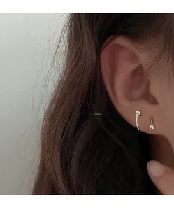 Detailed close-up of a silver spiral stud and ball earring set worn on the ear lobe