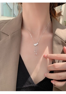 Détail d'un collier pendentif plume argenté avec des glands de chaîne et de petits cristaux