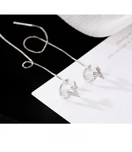 Detail showing long silver threader earrings with zircon-inlaid heartbeat design