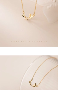 Close-up of golden butterfly pendant with clear zircon stones on delicate link chain