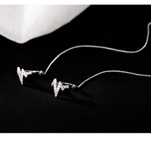 Macro shot of silver heartbeat earrings with zircon pavé and long box chains