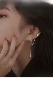 Detail of silver drop earrings and ear cuff with sparkling zircons on model
