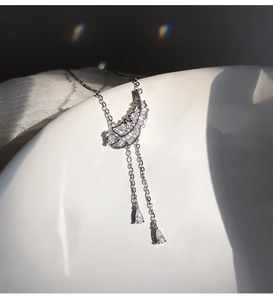 Détail du collier plume en argent avec glands de zircon sur une assiette blanche épurée
