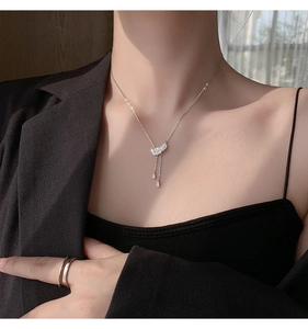 Gros plan d'un collier pendentif plume scintillant avec pompons en zircone sur mannequin
