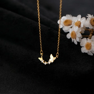 Elegant gold butterfly necklace with white zircons on black velvet background