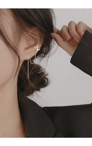 Detailed close-up of a silver lightning bolt ear cuff earring with long chain on model