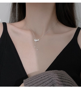 Détail du collier à pampilles plume argentée serti de zircons sur un pull noir chic