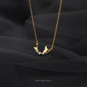 Elegant gold butterfly necklace with crystal accents and thin chain on mesh background