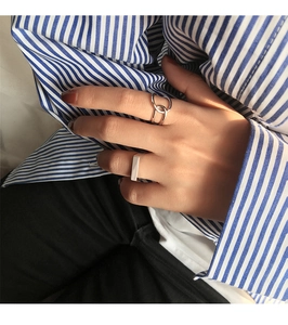 Close-up of minimalist silver rings including rectangular and interlocking designs
