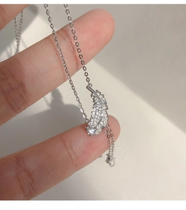 Détail macro du pendentif plume en argent serti de zircons sur un collier à chaîne en O